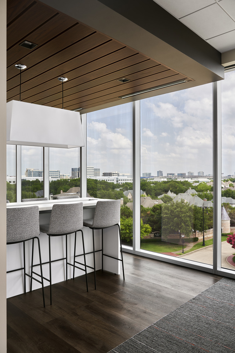 Interior of a multifamily residence with a view of a kitchen counter with bar stools and a view overlooking a city