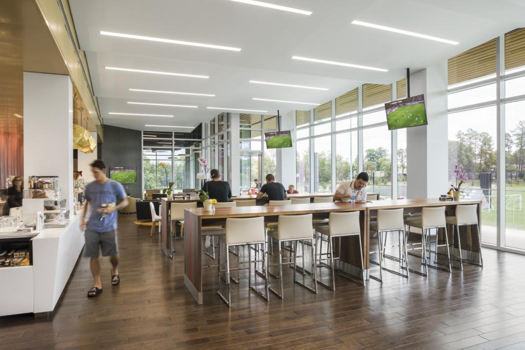 A cafeteria in a soccer training facility with tables and a food bar with people eating