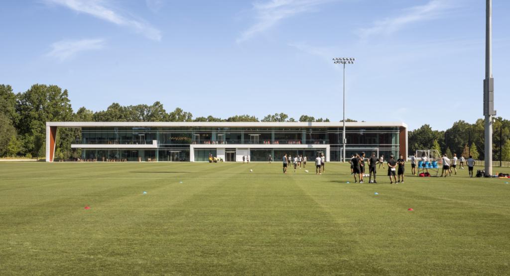 Outdoor soccer pitch with a training facility in the background